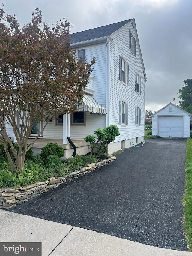 view of side of home featuring an outdoor structure, roof with shingles, aphalt driveway, and a detached garage