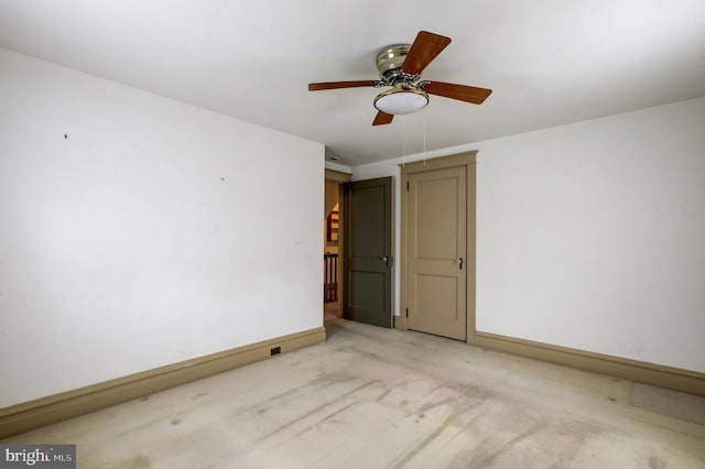 empty room featuring a ceiling fan, baseboards, and light carpet
