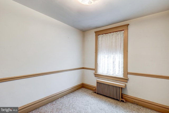 carpeted spare room with radiator and baseboards