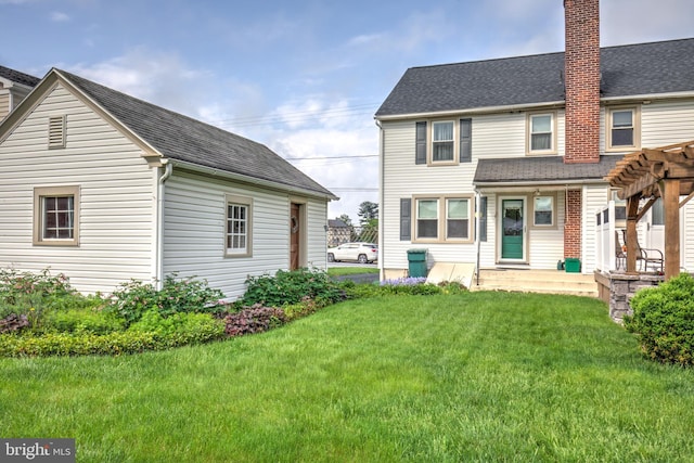 back of house featuring a chimney, a yard, a pergola, and a shingled roof