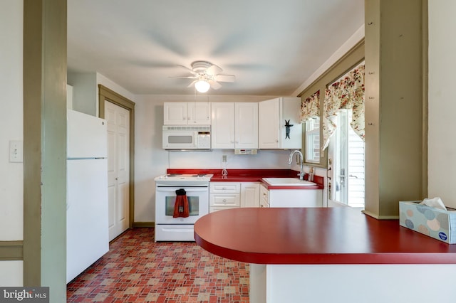 kitchen featuring white appliances, a sink, white cabinets, a ceiling fan, and a peninsula