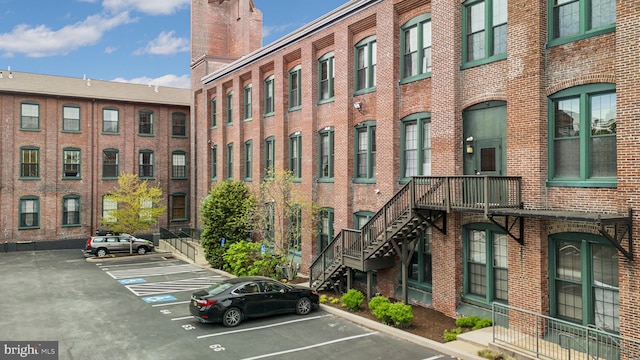 view of building exterior featuring uncovered parking and stairs