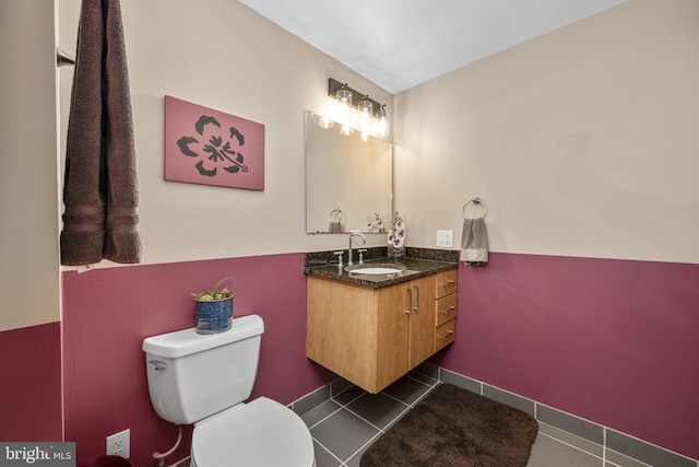 half bath with toilet, tile patterned flooring, and vanity