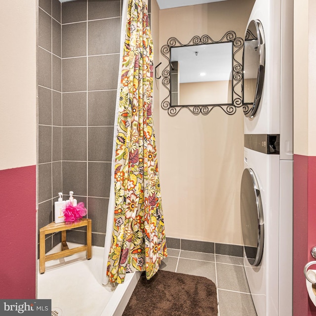 full bath featuring a stall shower, stacked washing maching and dryer, and tile patterned flooring