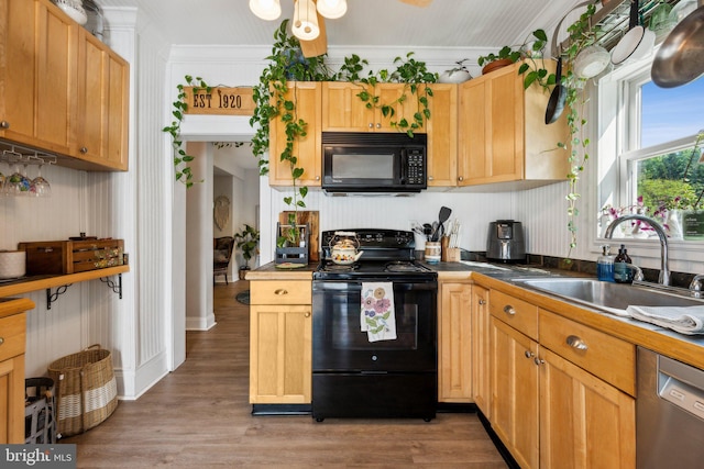 kitchen with a sink, ornamental molding, black appliances, dark countertops, and light wood-style floors
