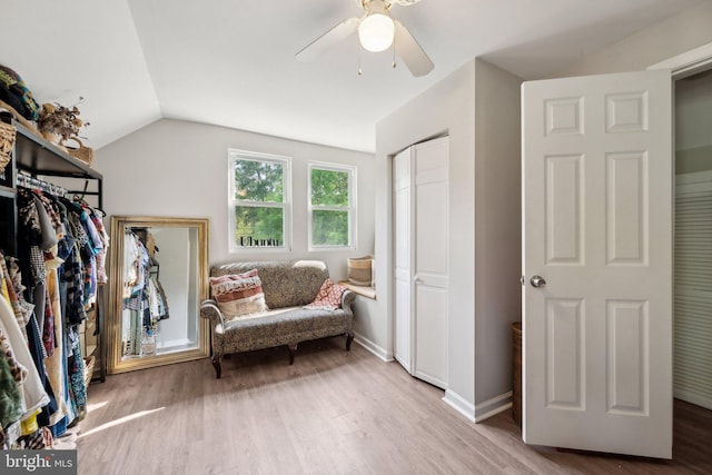 living area with baseboards, vaulted ceiling, ceiling fan, and wood finished floors