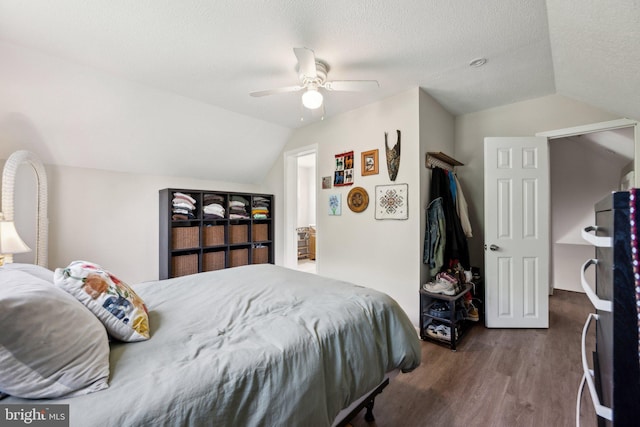 bedroom with lofted ceiling, a textured ceiling, refrigerator, dark wood-type flooring, and a ceiling fan
