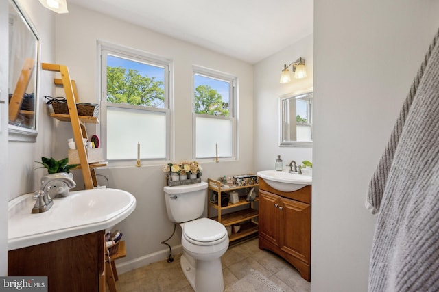 bathroom featuring a sink, toilet, baseboards, and tile patterned floors