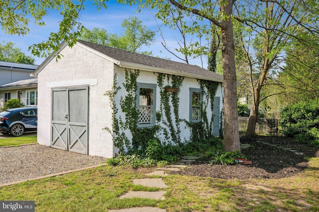 view of outbuilding featuring fence and an outbuilding