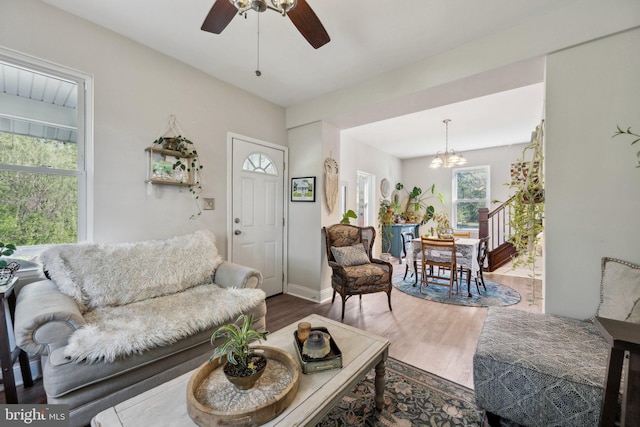 living room with baseboards, wood finished floors, and ceiling fan with notable chandelier