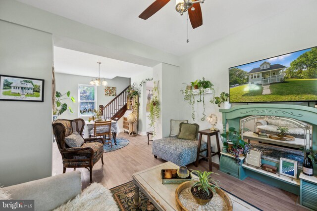 sitting room featuring ceiling fan with notable chandelier and wood finished floors
