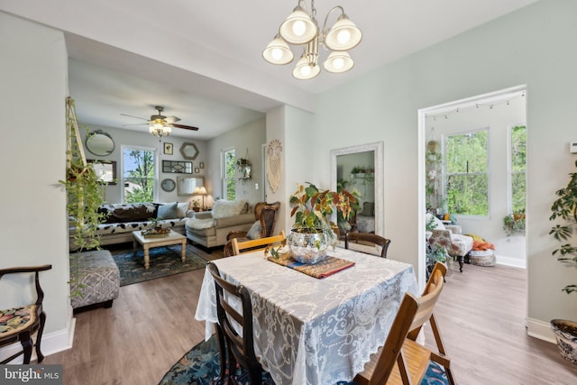 dining room with ceiling fan with notable chandelier, baseboards, and wood finished floors