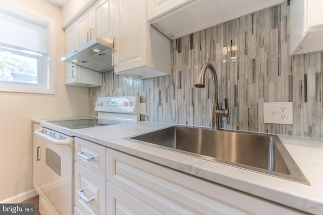 1650 Easton Rd, Hellertown, PA 18055 - kitchen featuring under cabinet range hood, a sink, white cabinetry, tasteful backsplash, and electric range