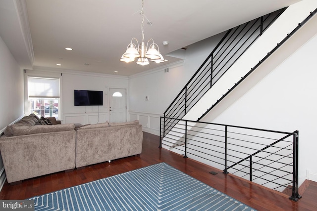 living area featuring a decorative wall, wood finished floors, ornamental molding, recessed lighting, and an inviting chandelier
