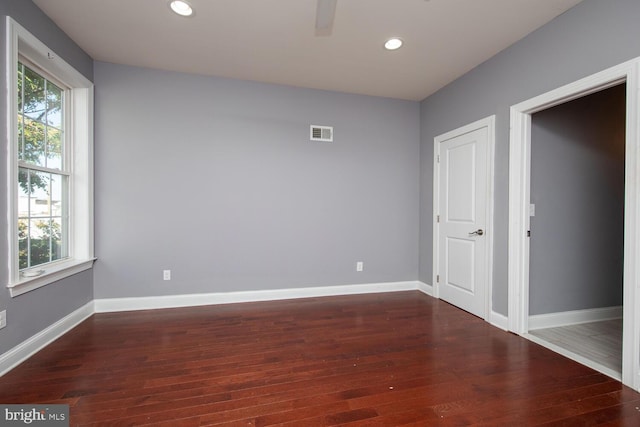unfurnished room with a healthy amount of sunlight, visible vents, and wood finished floors