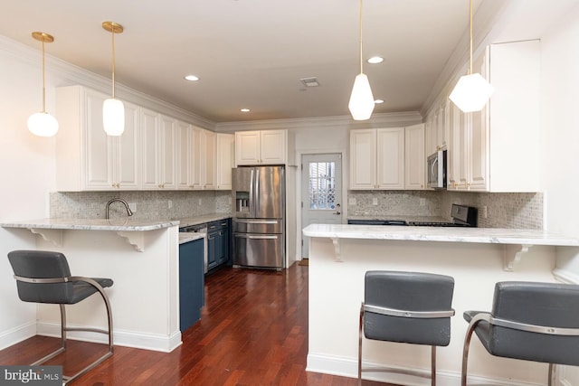 kitchen with a peninsula, appliances with stainless steel finishes, dark wood-type flooring, and tasteful backsplash