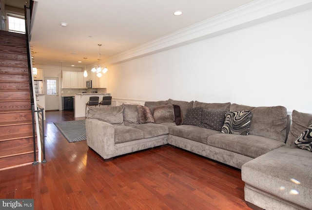 living room featuring dark wood-type flooring, recessed lighting, stairway, crown molding, and an inviting chandelier