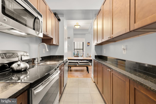 1613 Harvard St NW Unit 105, Washington, DC 20009 - kitchen featuring stainless steel appliances, a sink, dark stone countertops, and light tile patterned floors