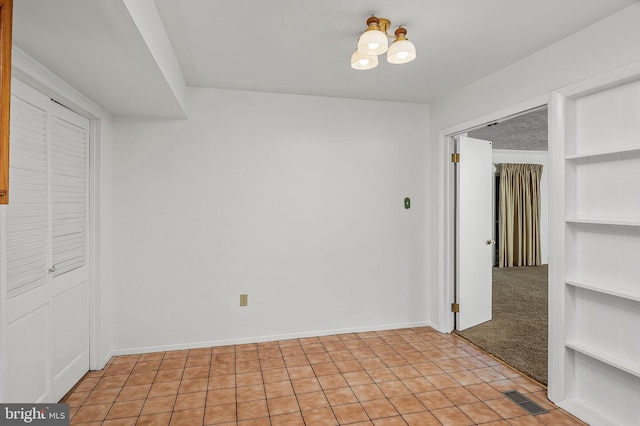 unfurnished room featuring built in features, light tile patterned floors, and baseboards