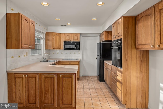 kitchen featuring black appliances, a sink, a peninsula, light countertops, and tasteful backsplash