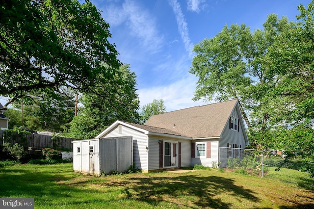 back of house featuring a storage shed, an outbuilding, and roof with shingles