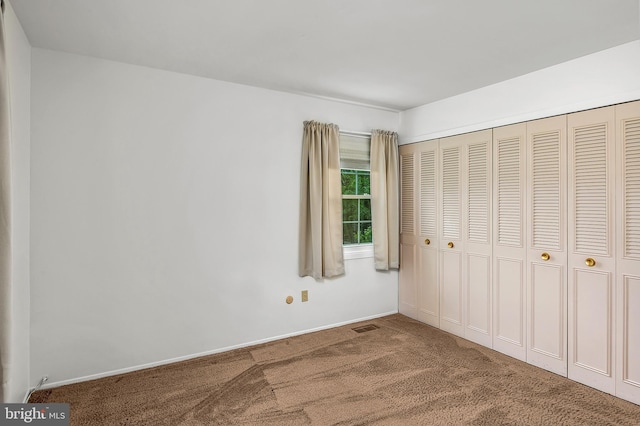 unfurnished bedroom featuring carpet, a closet, and baseboards