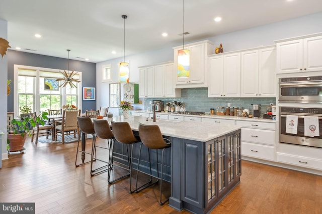 23593 Robalo Rd, Frankford, DE 19945 - kitchen with white cabinets, stainless steel appliances, backsplash, wood finished floors, and recessed lighting