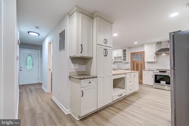 6488 Davis Ford Rd, Manassas, VA 20111 - kitchen with stove, freestanding refrigerator, wall chimney exhaust hood, light wood-style flooring, and white cabinetry