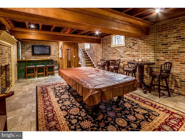 game room with stone tile flooring, beam ceiling, pool table, and brick wall