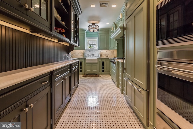 kitchen featuring visible vents, decorative backsplash, green cabinetry, light countertops, and appliances with stainless steel finishes