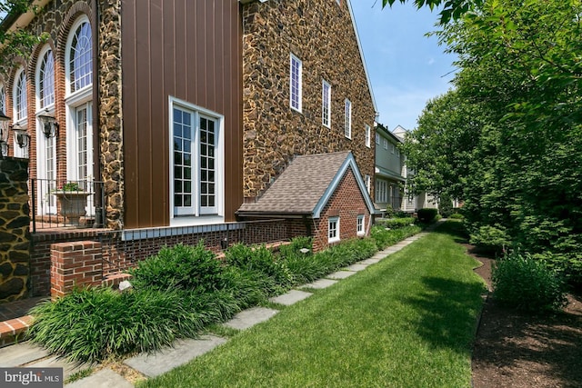view of side of property with stone siding, a yard, and brick siding