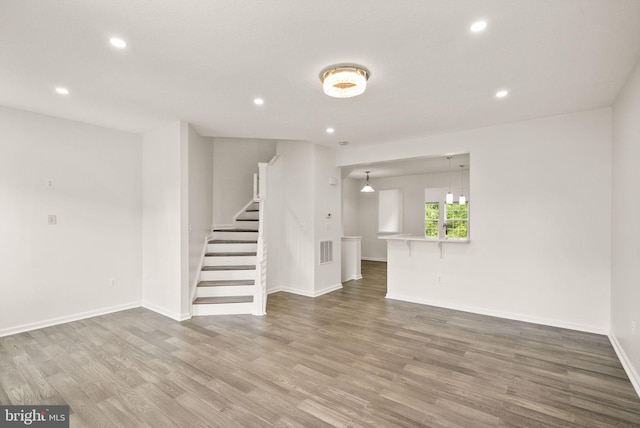 unfurnished living room featuring stairs, recessed lighting, wood finished floors, and baseboards