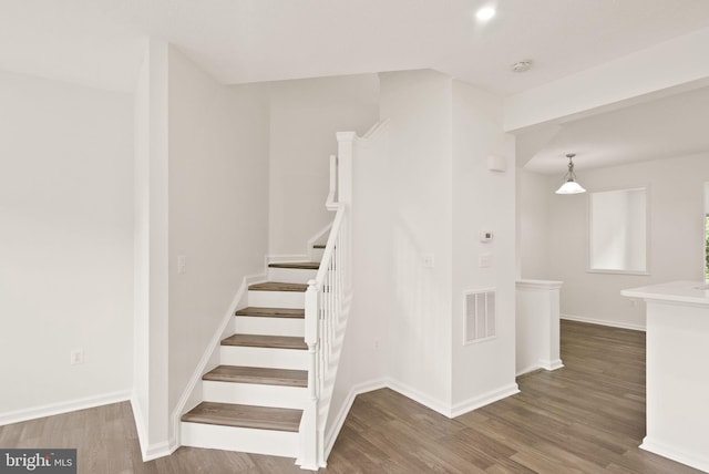 stairway with wood finished floors and baseboards
