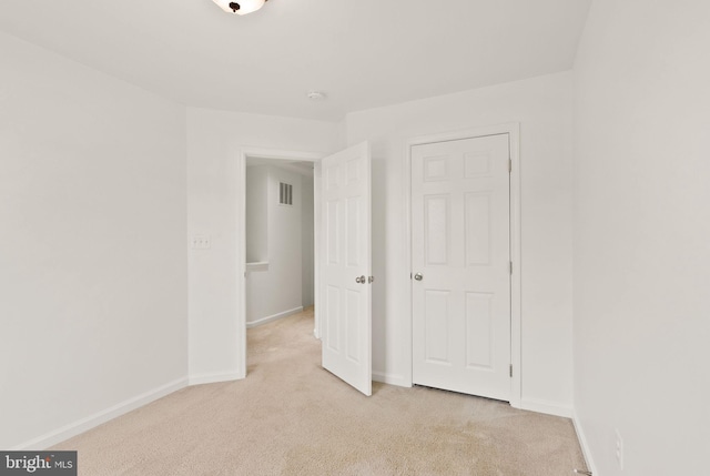 unfurnished bedroom featuring light colored carpet and baseboards