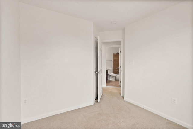 spare room featuring light carpet, baseboards, and a smoke detector