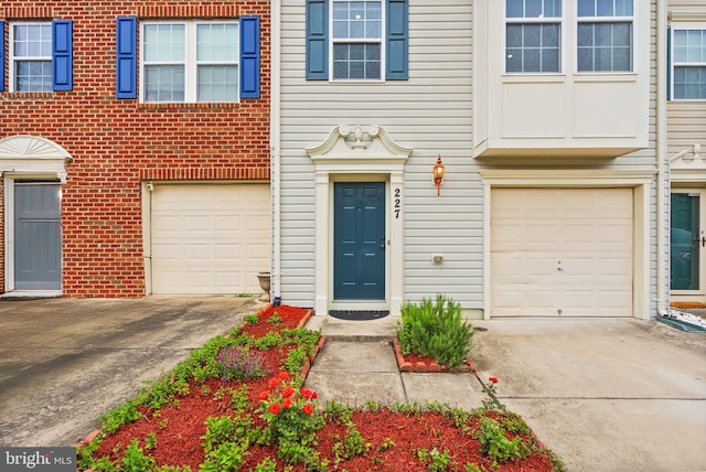 entrance to property with a garage, driveway, and brick siding