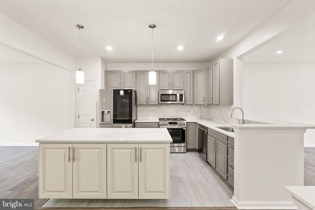 kitchen featuring stainless steel appliances, gray cabinets, a center island, tasteful backsplash, and a sink