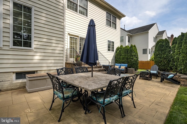 view of patio / terrace featuring an outdoor living space with a fire pit, entry steps, fence, and outdoor dining space