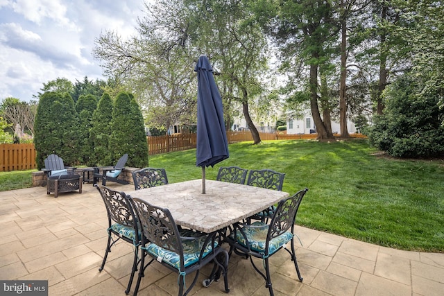 view of patio with an outdoor fire pit, outdoor dining area, and a fenced backyard