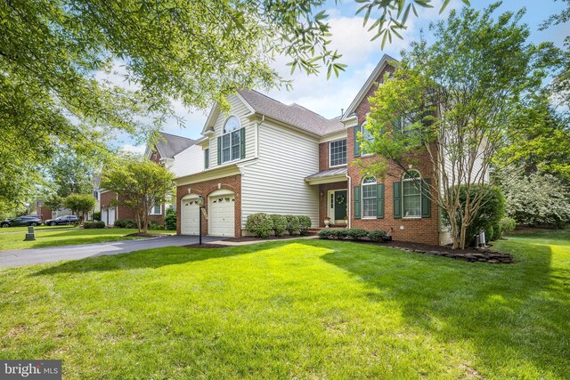 traditional-style house with an attached garage, a front lawn, brick siding, and driveway