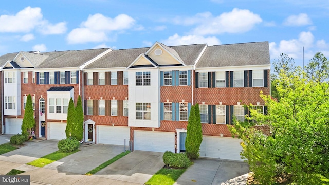 view of property featuring a garage, driveway, and brick siding