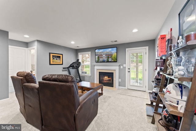 living area featuring light carpet, a fireplace with flush hearth, baseboards, and recessed lighting