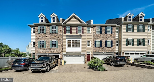 townhome / multi-family property featuring stone siding, driveway, and an attached garage