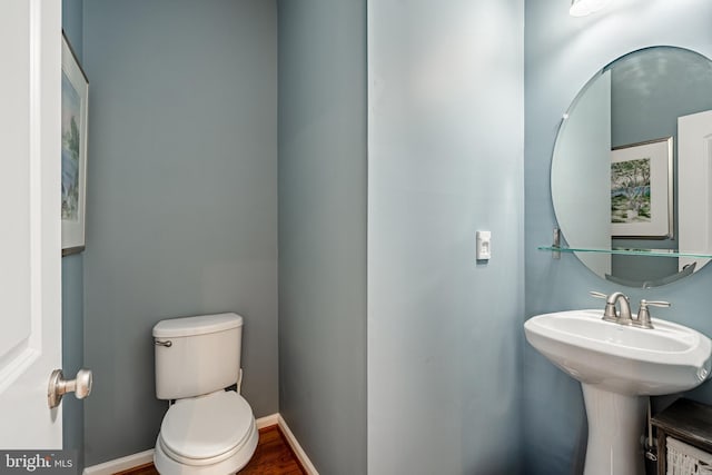 bathroom featuring toilet, wood finished floors, and baseboards