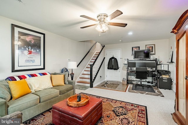 living area featuring ceiling fan, a desk, stairs, and carpet floors