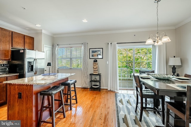 kitchen with stainless steel fridge, a chandelier, light wood finished floors, plenty of natural light, and crown molding