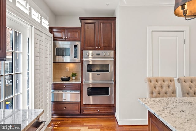 44521/2 Macarthur Blvd NW, Washington, DC 20007 - kitchen featuring stainless steel appliances, a warming drawer, tasteful backsplash, light wood-style floors, and light stone countertops