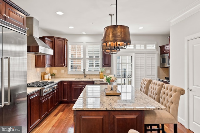 44521/2 Macarthur Blvd NW, Washington, DC 20007 - kitchen with stainless steel appliances, a sink, wall chimney range hood, light wood-type flooring, and a breakfast bar area
