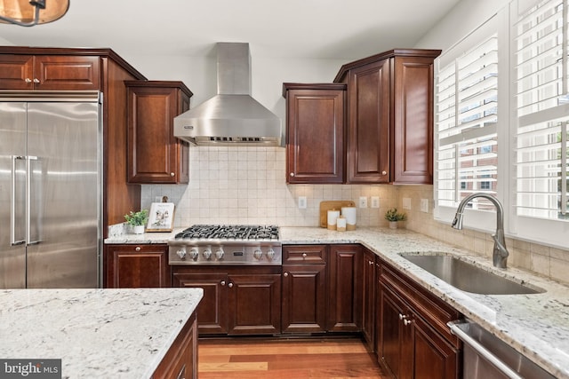 44521/2 Macarthur Blvd NW, Washington, DC 20007 - kitchen with appliances with stainless steel finishes, wall chimney exhaust hood, a sink, light wood finished floors, and decorative backsplash