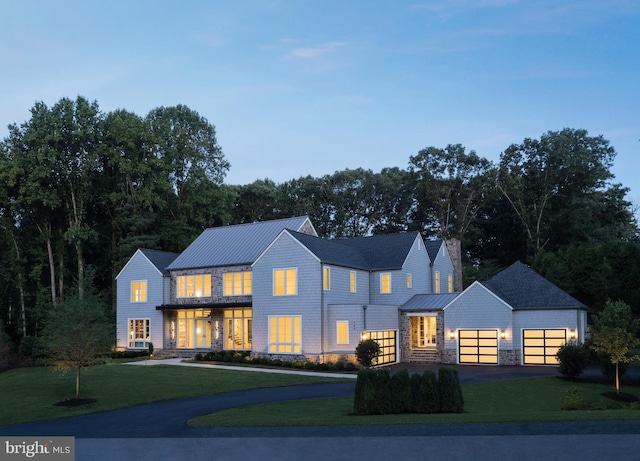 modern farmhouse style home with a garage, metal roof, aphalt driveway, a front lawn, and a standing seam roof